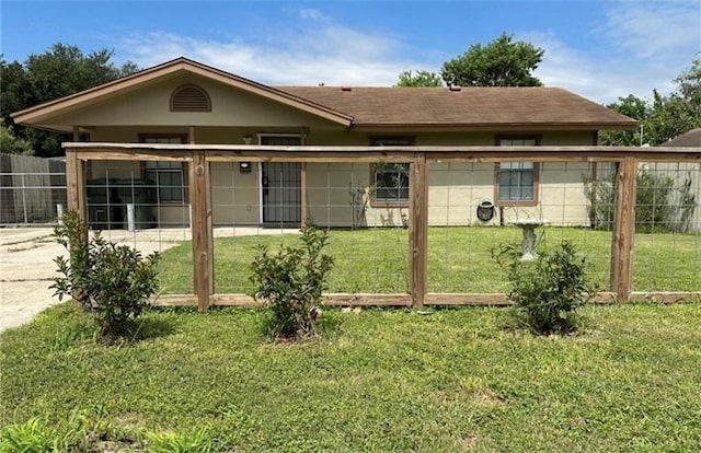 back of property with concrete driveway, a lawn, and fence