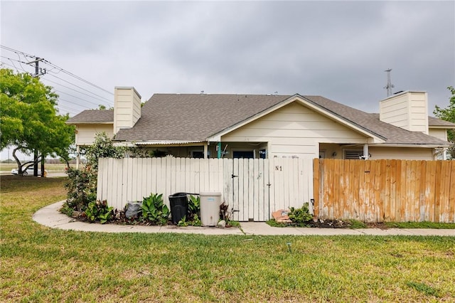 7202 Mansions Dr Unit N1, Corpus Christi, TX 78414 - view of home's exterior featuring a chimney, fence, roof with shingles, and a yard
