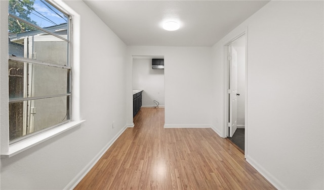 hallway featuring light wood-type flooring and a wall unit AC