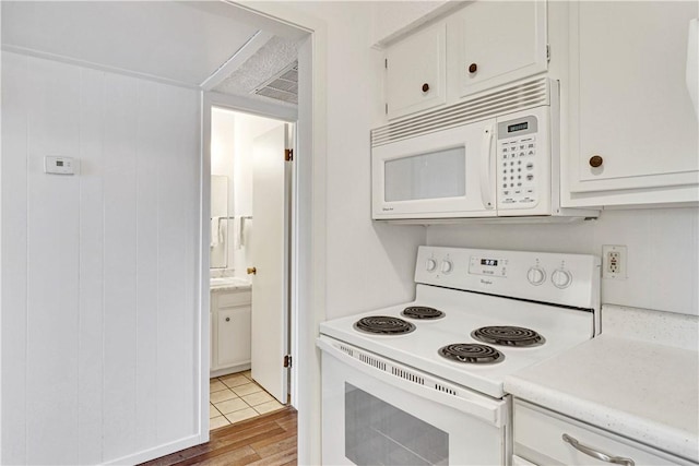 kitchen with light wood-type flooring, white appliances, and white cabinetry