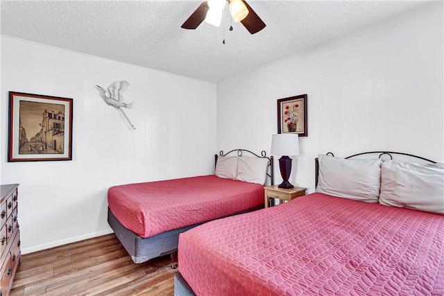 bedroom with ceiling fan, hardwood / wood-style floors, and a textured ceiling