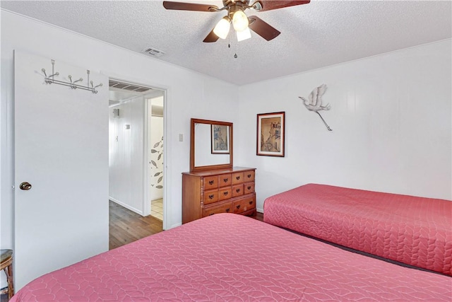 bedroom with ceiling fan, dark hardwood / wood-style flooring, and a textured ceiling