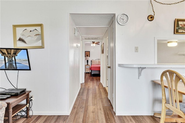 hall with hardwood / wood-style floors and a textured ceiling