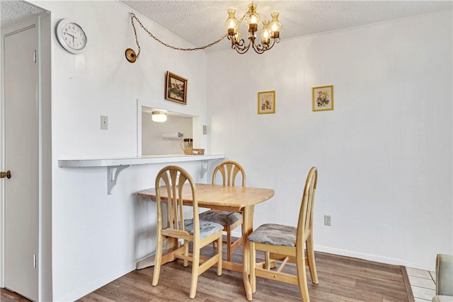 dining room featuring hardwood / wood-style flooring, a textured ceiling, and an inviting chandelier