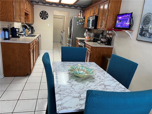 kitchen with decorative backsplash, appliances with stainless steel finishes, sink, and light tile patterned flooring