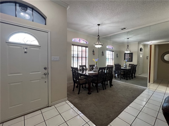 foyer entrance with light tile patterned flooring, a textured ceiling, and ornamental molding