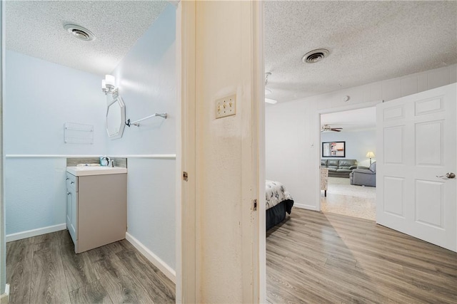438 Pennington Dr, Corpus Christi, TX 78412 - bathroom featuring a textured ceiling, vanity, wood finished floors, connected bathroom, and baseboards