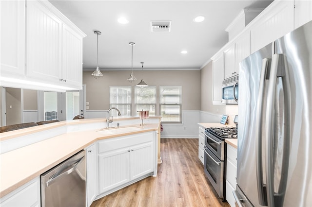 215 Sandollar Cir, Fulton, TX 78358 - kitchen with appliances with stainless steel finishes, a sink, white cabinets, light wood finished floors, and crown molding