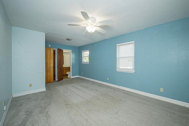 unfurnished bedroom featuring connected bathroom, ceiling fan, and light carpet