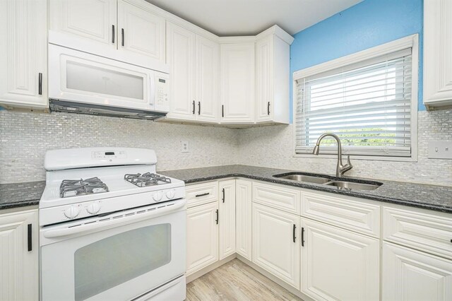 kitchen featuring white cabinetry, sink, dark stone countertops, light hardwood / wood-style floors, and white appliances