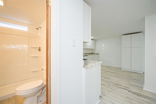 bathroom with a shower, hardwood / wood-style flooring, and toilet