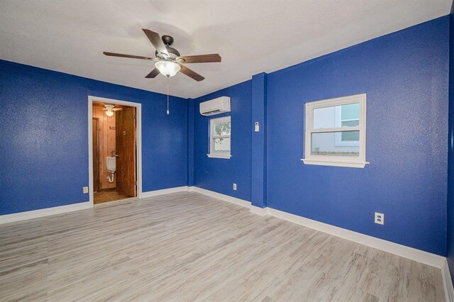 unfurnished room featuring a wall mounted AC, ceiling fan, and light hardwood / wood-style floors