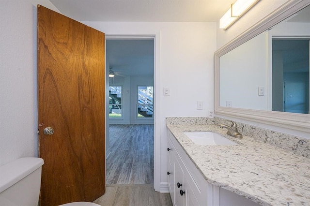 bathroom with wood-type flooring, vanity, toilet, and ceiling fan