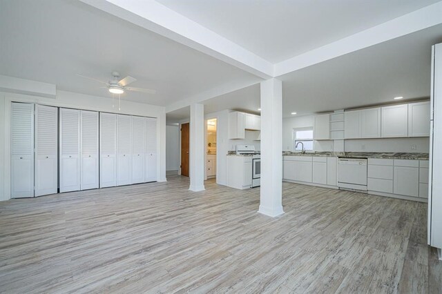 unfurnished living room featuring light hardwood / wood-style flooring, ceiling fan, and sink