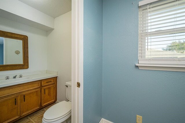 bathroom featuring tile patterned flooring, vanity, a textured ceiling, and toilet