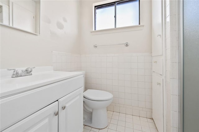 bathroom with a shower with shower door, tile patterned flooring, toilet, tile walls, and vanity