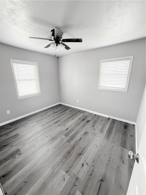 9047 County Road 471, Mathis, TX 78368 - spare room featuring plenty of natural light, wood finished floors, ceiling fan, a textured ceiling, and baseboards