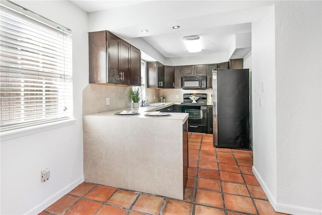 kitchen featuring black appliances, plenty of natural light, dark brown cabinetry, and kitchen peninsula