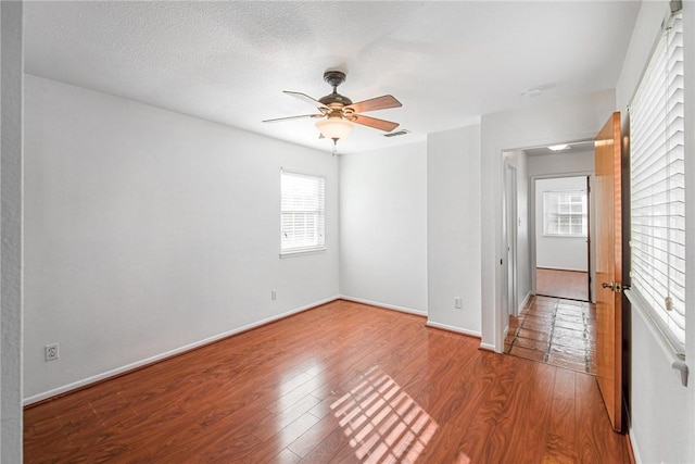 unfurnished room featuring ceiling fan, wood-type flooring, and a textured ceiling