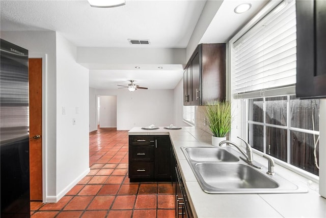 kitchen with ceiling fan, sink, dark tile patterned floors, and dark brown cabinets