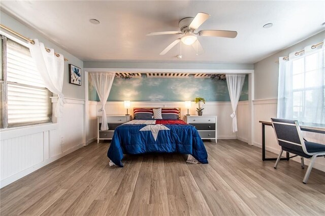 938 E Lakeside Dr, Corpus Christi, TX 78418 - bedroom with wood finished floors, wainscoting, a ceiling fan, and a decorative wall