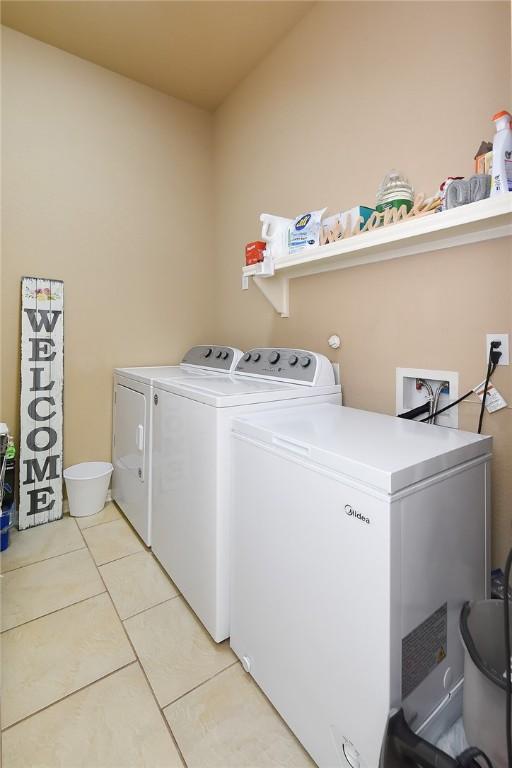 laundry area with light tile patterned flooring and washer and clothes dryer