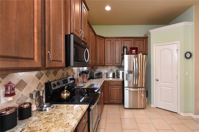 kitchen featuring light stone counters, appliances with stainless steel finishes, light tile patterned flooring, and backsplash