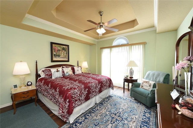 bedroom featuring ceiling fan, ornamental molding, wood-type flooring, and a raised ceiling