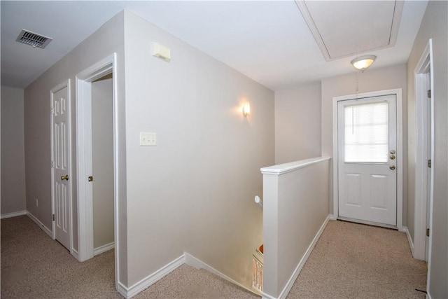 hallway featuring attic access, visible vents, baseboards, and an upstairs landing