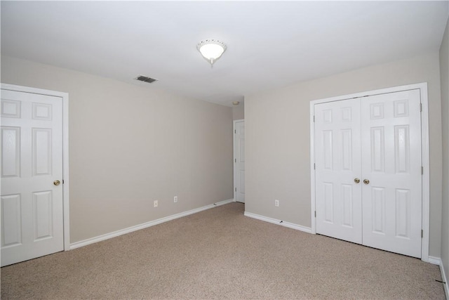 unfurnished bedroom featuring carpet floors, a closet, visible vents, and baseboards