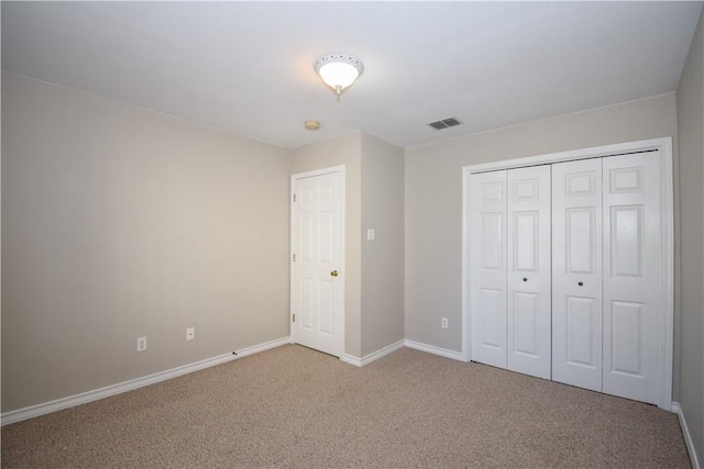 unfurnished bedroom featuring carpet floors, visible vents, baseboards, and a closet