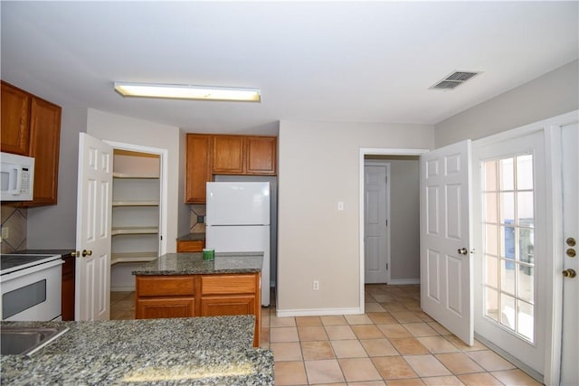 kitchen with visible vents, backsplash, brown cabinetry, white appliances, and baseboards