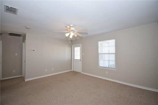 carpeted spare room with visible vents, ceiling fan, and baseboards