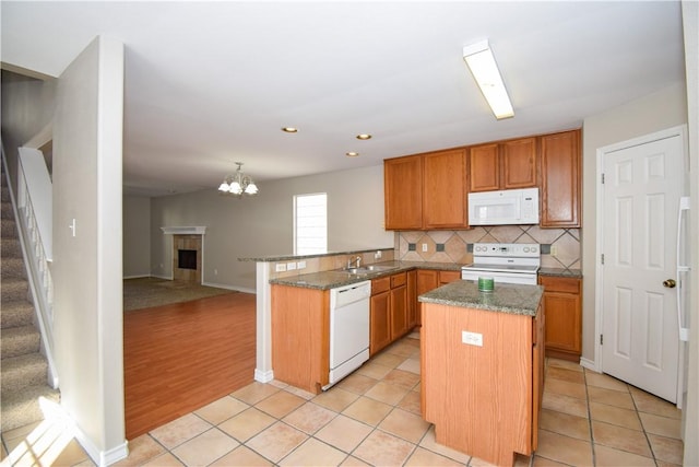 kitchen featuring white appliances, tasteful backsplash, light tile patterned floors, a peninsula, and stone counters