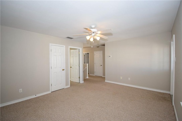 spare room with a ceiling fan, light colored carpet, visible vents, and baseboards