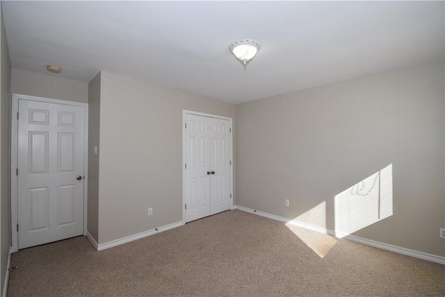 unfurnished bedroom with carpet floors, a closet, and baseboards