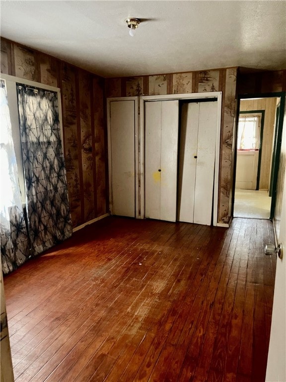 unfurnished bedroom featuring wood-type flooring and wooden walls