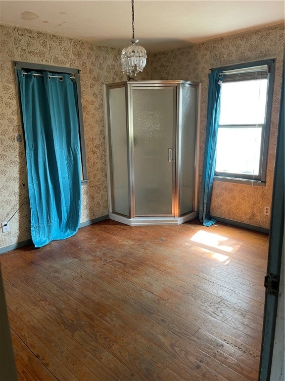 unfurnished room with hardwood / wood-style flooring and an inviting chandelier