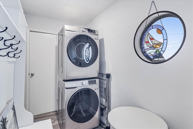 laundry room featuring stacked washing maching and dryer and hardwood / wood-style floors