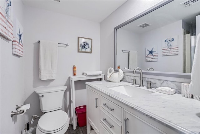 bathroom with toilet, vanity, and wood-type flooring