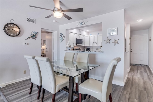 dining space with hardwood / wood-style floors and ceiling fan