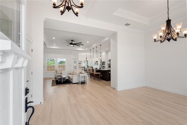 living room featuring ornamental molding, a tray ceiling, light hardwood / wood-style floors, and ceiling fan with notable chandelier