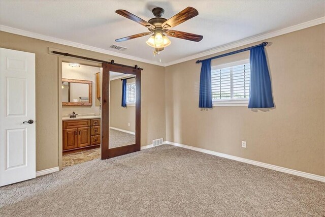 11129 Mulholland Dr, Corpus Christi, TX 78410 - unfurnished bedroom featuring light carpet, a barn door, multiple windows, ornamental molding, and ensuite bathroom