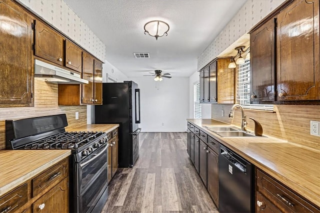 11129 Mulholland Dr, Corpus Christi, TX 78410 - kitchen with black appliances, under cabinet range hood, dark wood finished floors, ceiling fan, and backsplash