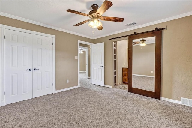 11129 Mulholland Dr, Corpus Christi, TX 78410 - unfurnished bedroom featuring a barn door, carpet, a closet, ornamental molding, and ceiling fan