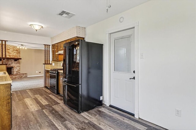 11129 Mulholland Dr, Corpus Christi, TX 78410 - kitchen with black appliances, dark wood finished floors, a brick fireplace, backsplash, and brown cabinetry