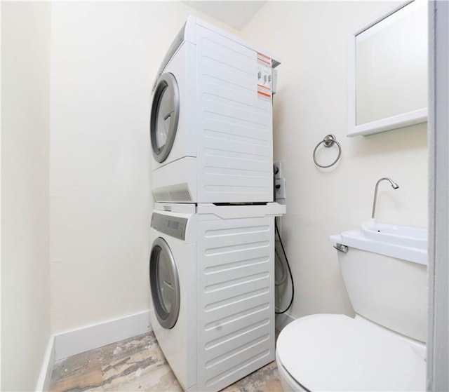 laundry area with stacked washing machine and dryer and baseboards