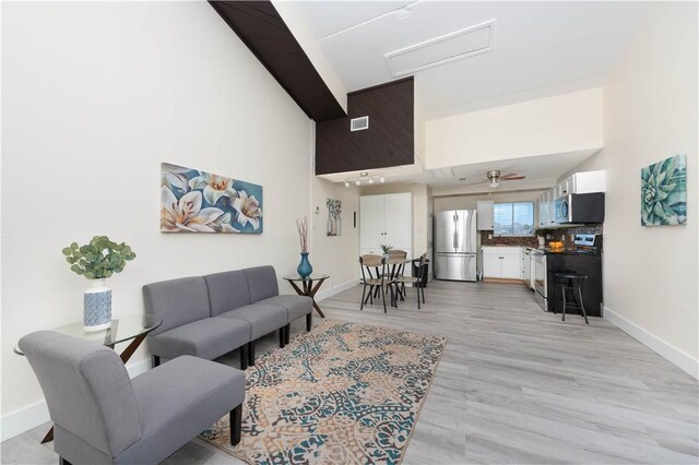 living area featuring attic access, light wood finished floors, and ceiling fan