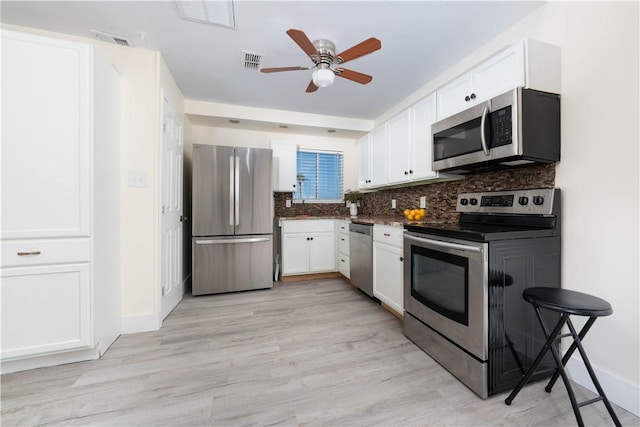 kitchen featuring appliances with stainless steel finishes, white cabinets, ceiling fan, decorative backsplash, and light wood-style floors