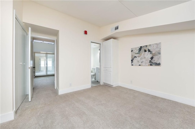 unfurnished bedroom with light colored carpet and ensuite bath